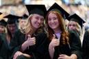 Two female students give the thumbs up at commencement